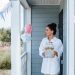 Woman holding lemonade jar at decorated house entrance for a summer party.