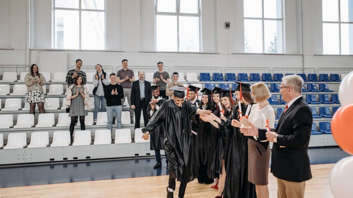 Graduates celebrate their achievement in a gymnasium with friends and family cheering.