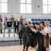 Graduates celebrate their achievement in a gymnasium with friends and family cheering.
